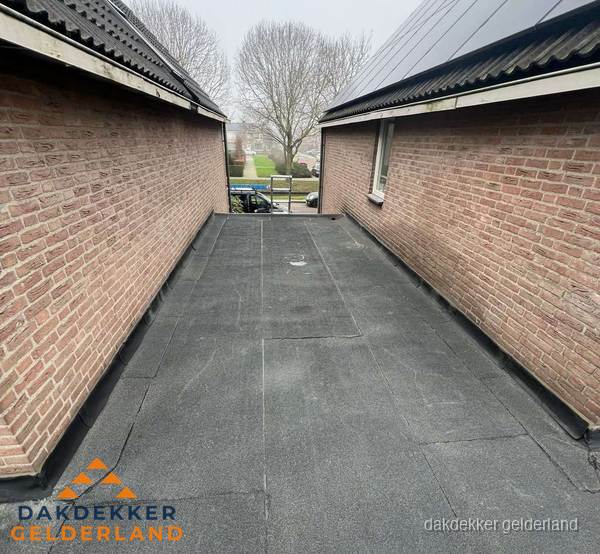 Plat dak met bitumen dakbedekking tussen bakstenen muren in Gelderland Plat dak met bitumen dakbedekking tussen bakstenen muren in Gelderland