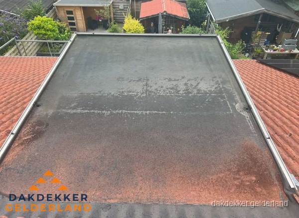 Verouderd plat dak met slijtage tussen schuine daken in Gelderland Verouderd plat dak met slijtage tussen schuine daken in Gelderland