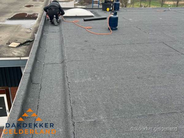 Dakdekker repareert bitumen dakbedekking op groot plat dak in Gelderland Dakdekker repareert bitumen dakbedekking op groot plat dak in Gelderland