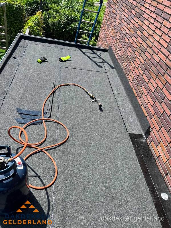 Plat dak met bitumen en brandgereedschap van dakdekkersbedrijf in Gelderland
